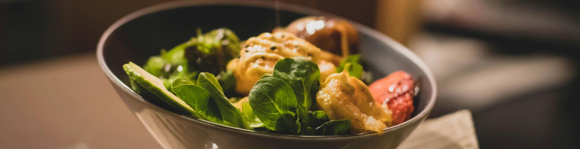 Delicious bowl of salad with fresh greens and grilled chicken served on a wooden platter.