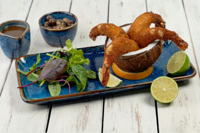 Delicious crispy fried shrimp served on a ceramic tray with fresh salad and lime garnish.