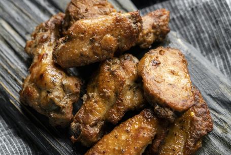 Appetizing barbecue chicken wings served with rich dipping sauce on rustic wooden board.
