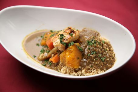 Mouth-watering chicken curry with vegetables served over rice in a bowl on a red table setting.