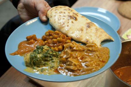 A vibrant blue plate featuring a variety of Indian curries and naan bread, served indoors.