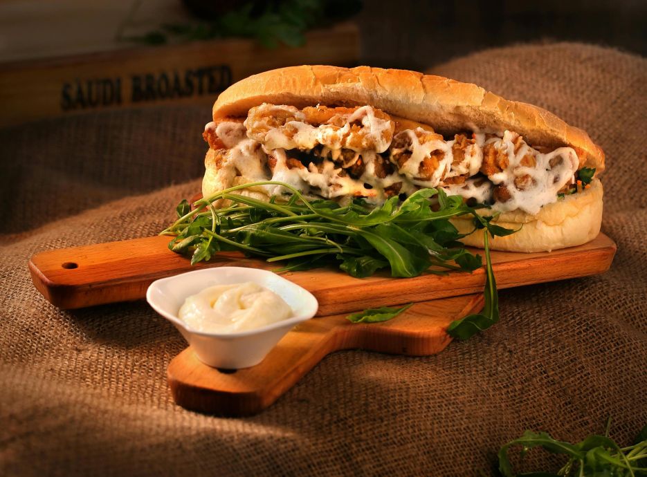 Delicious chicken sandwich with mayonnaise and greens served on a wooden board.