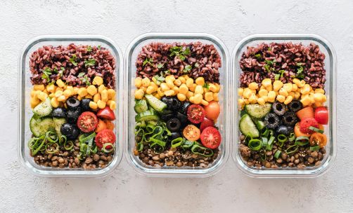 Colorful healthy meal prep with corn, olives, tomatoes, and lentils in glass containers. Perfect for mindful eating.