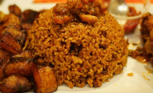 A tempting plate of Jollof rice accompanied by savory fried plantains. Perfect meal idea.