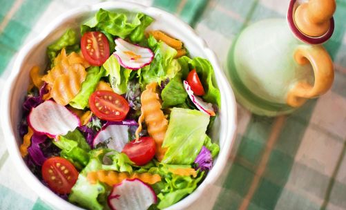 Colorful fresh vegetable salad with cherry tomatoes in a white bowl.