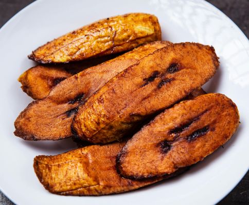 Close-up of crispy fried plantains served on a white plate. Mouth-watering and tasty.