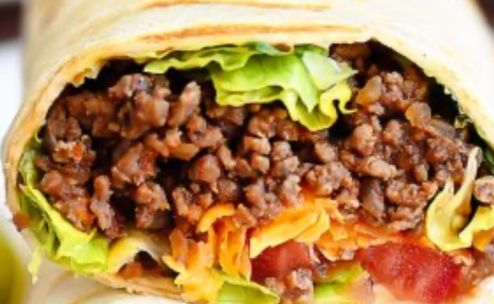 Tasty chicken wrap filled with creamy sauce on a wooden cutting board.