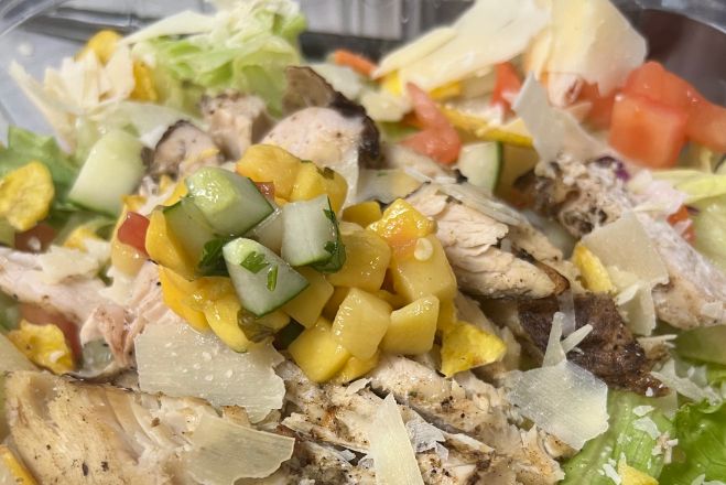 Delicious chicken salad with spinach, feta cheese, and creamy sauce on a white plate.