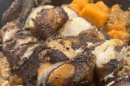 Tantalizing Caribbean jerk chicken served with rice and beans and fried plantains on a square plate.