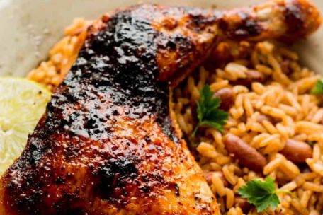 Savory roasted chicken on a bed of rice with lentils, accented by spicy and fresh green sides.