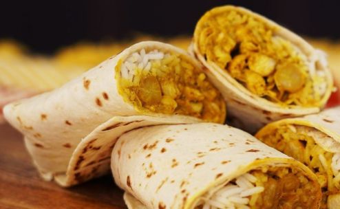 Close-up of a tasty grilled chicken wrap with fresh ingredients on a plate.