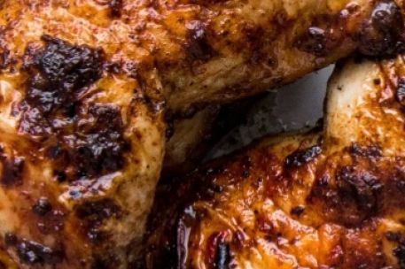 Close-up of a deliciously roasted chicken dish served with garnish, highlighting fine cuisine.